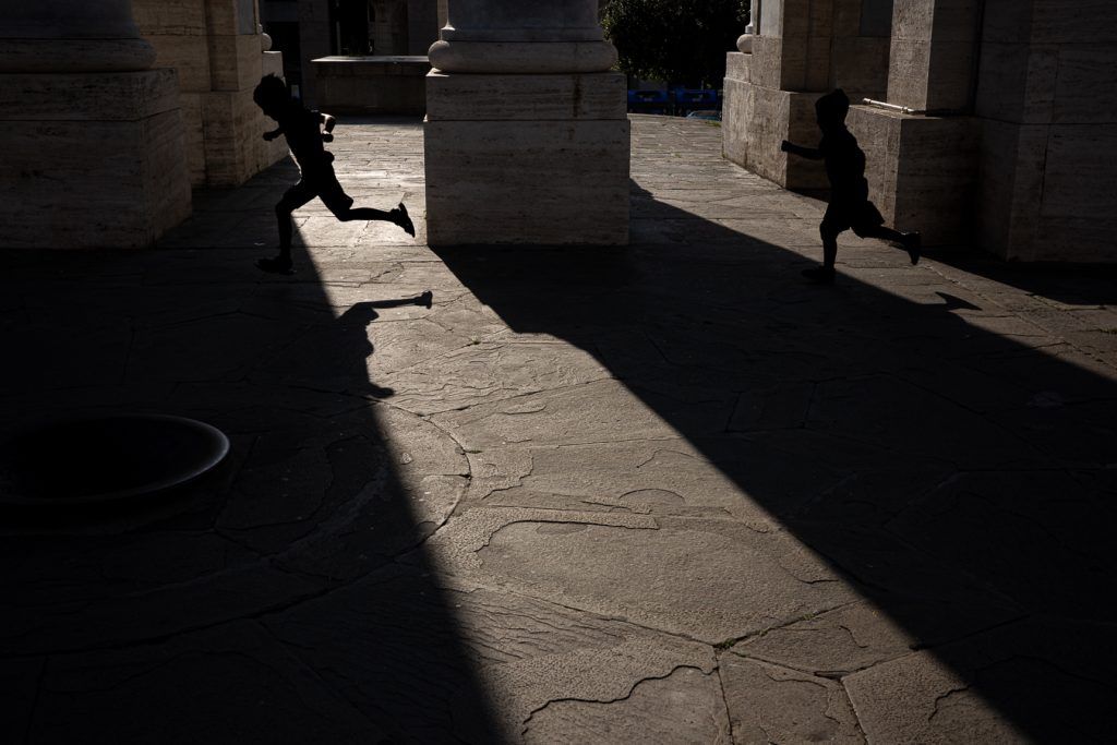 Dos niños corren bajo el Arco Della Vittoria, en Génova.